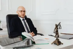 Юрист аналізує судовий позов проти OpenAI у світлому офісі з ноутбуком і паперами.