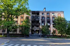 Пошкоджена будівля університету в Києві після ракетного удару, поруч працюють рятувальники.