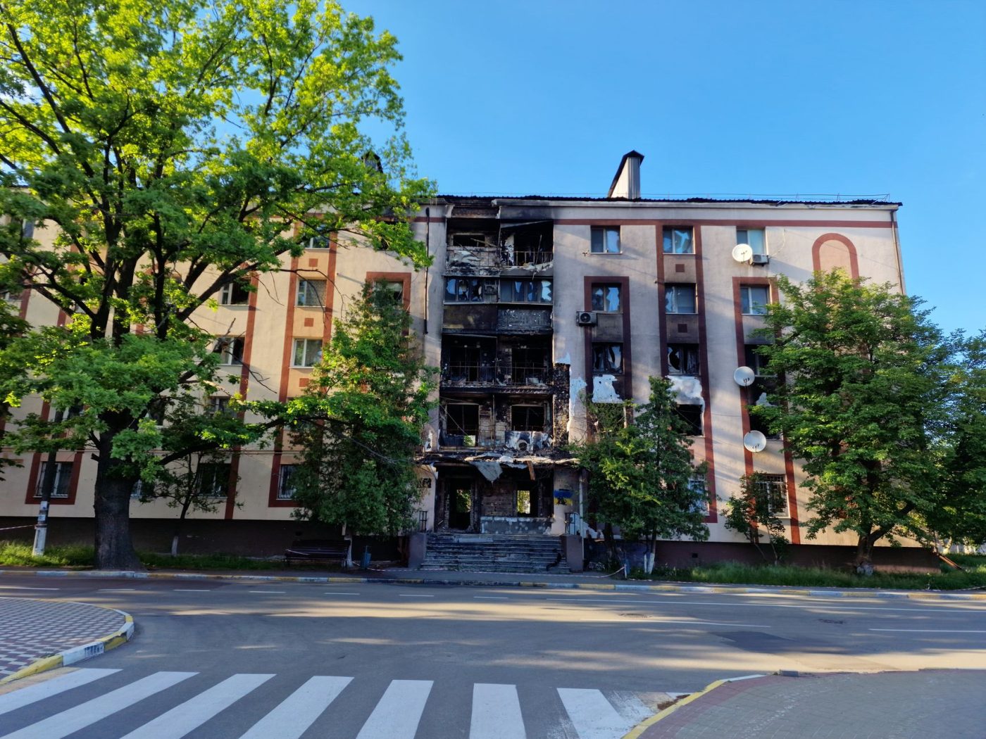 Пошкоджена будівля університету в Києві після ракетного удару, поруч працюють рятувальники.